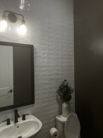 Bathroom with textured tile wall and dark vanity